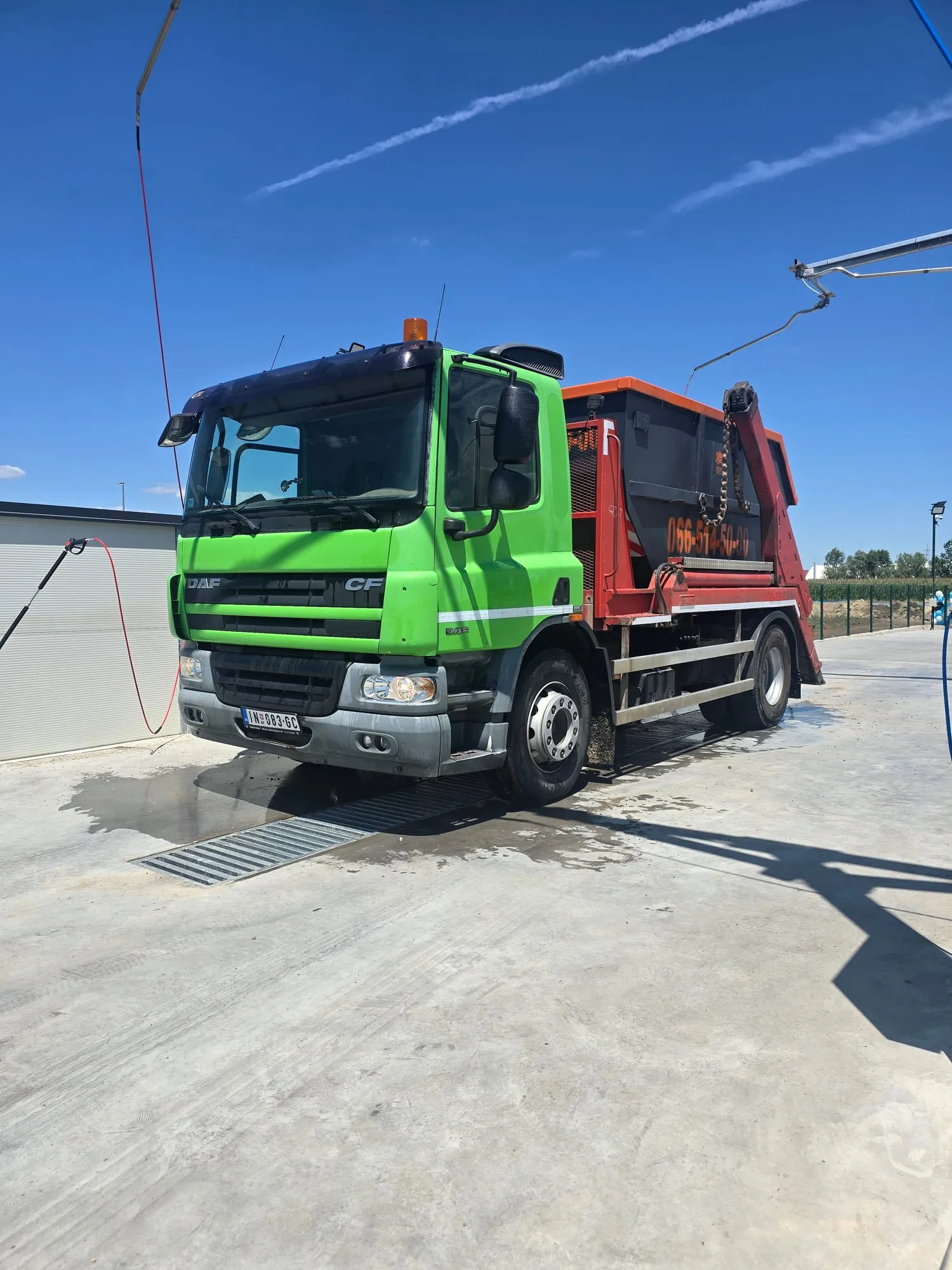 Zeleni kamion Tenen Transporta sa kontejnerom na betonskom platou